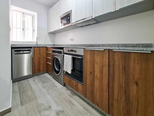 cocina con armarios de madera, lavadora y secadora en Villa Playa y Centro Exclusive Accommodation, en Benidorm