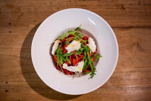 a white plate with a salad on a wooden table at Apartments Rose Garden in Děčín