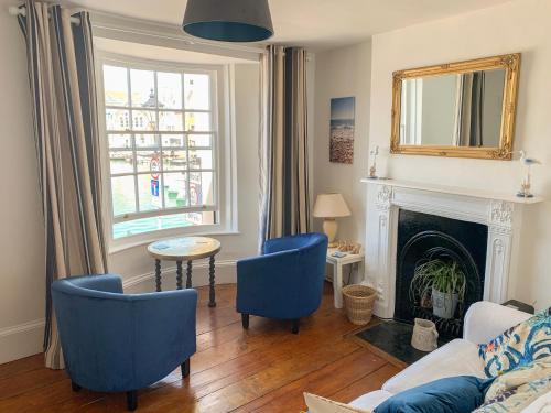 ein Wohnzimmer mit blauen Stühlen und einem Kamin in der Unterkunft The Ferryman in Weymouth