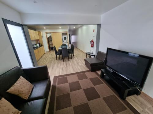 a living room with a large flat screen tv and a table at Casa do João Bento in Água de Alto