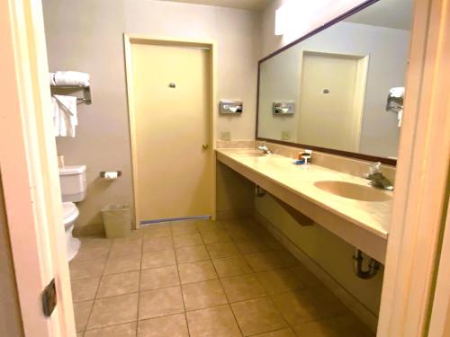 a bathroom with a sink and a toilet and a mirror at Ramada by Wyndham Los Angeles/Wilshire Center in Los Angeles
