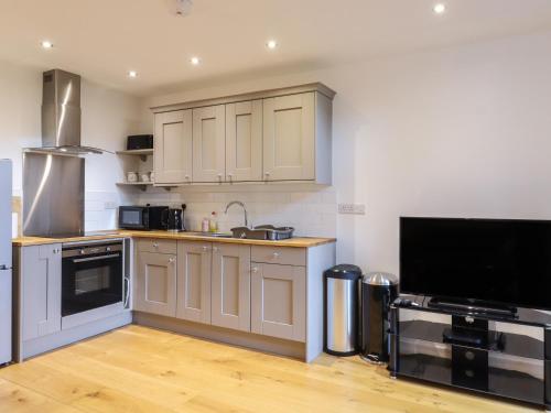 a kitchen with white cabinets and a flat screen tv at Grange Barn in Hessett