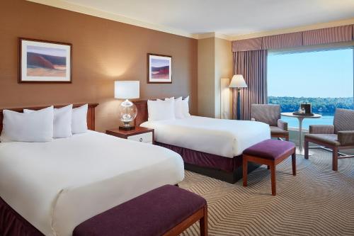 a hotel room with two beds and a chair at Harrah's Metropolis, A Caesars Destination in Metropolis