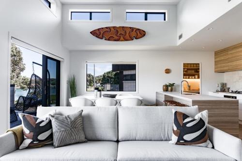 a living room with a couch and a kitchen at Harbourview Haven in Raglan