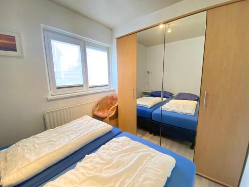 een slaapkamer met 2 bedden en een spiegel bij Appartement Walvis nr. 16 in Vrouwenpolder