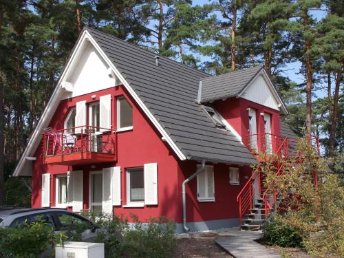 een rood huis met een zwart dak bij Apartment house, Trassenheide in Trassenheide