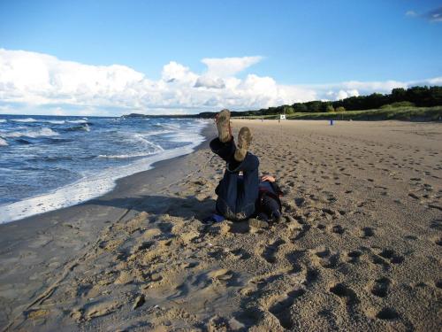 a woman sitting on a beach with her hands in the air at Apartment in Trassenheide for 4 Personen in Trassenheide