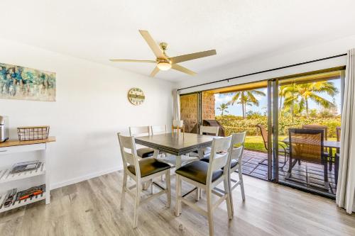 a dining room with a table and chairs and a ceiling fan at Newly Renovated Condo with SUP Paddle Boards and Golf Clubs Included in Kailua-Kona