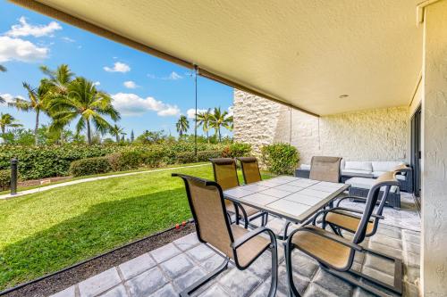 a patio with a table and chairs and a lawn at Newly Renovated Condo with SUP Paddle Boards and Golf Clubs Included in Kailua-Kona