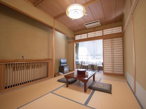 uma sala de estar com uma mesa e uma televisão num quarto em Hotel Nosegawa em Nosegawa