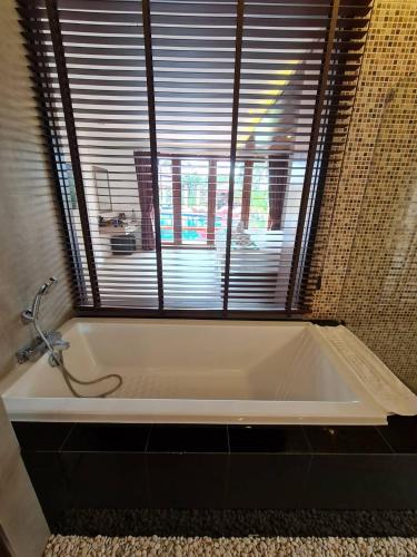 a white bath tub in a bathroom with a window at Elegancy Resort Hua Hin in Hua Hin