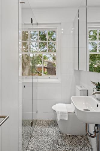 a white bathroom with a tub and a sink at Mulwarree Avenue Apartments by Urban Rest in Sydney