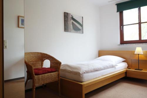 a bedroom with a bed and a chair and a window at Pension am Helenenwall in Cologne