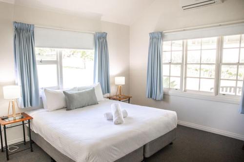 a bedroom with a large bed with two windows at Audrey Wilkinson Vineyard in Pokolbin