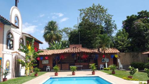 a house with a swimming pool and a church at Hotel Cabañas De Rozo in Rozo