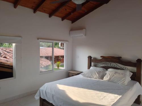 a bedroom with a bed with white sheets and a window at Hotel Cabañas De Rozo in Rozo