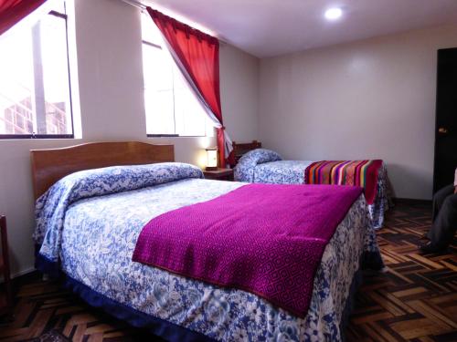 a bedroom with two beds with purple blankets at Hostal los Uros in Puno