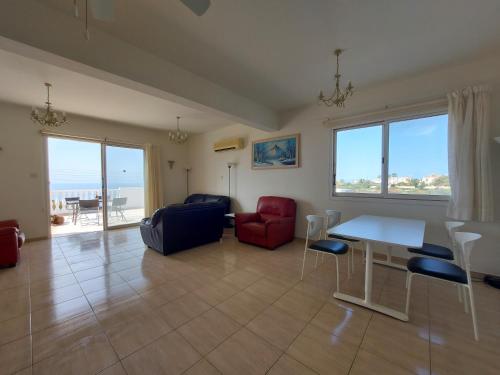 Una sala de estar con una mesa y sillas y el océano. en SEA CAVES suite, en Peyia