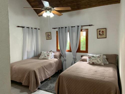 a bedroom with two beds and a ceiling fan at Villa Maria Paula in Jarabacoa