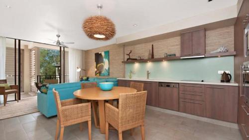 a kitchen and living room with a blue couch and a table at Penthouse - Palm Cove in Palm Cove