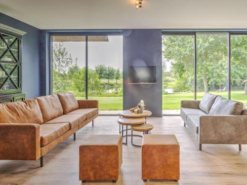 a living room with brown leather furniture and large windows at Tranquil Farmhouse in Rijsbergen with Hot Tub and Garden in Rijsbergen