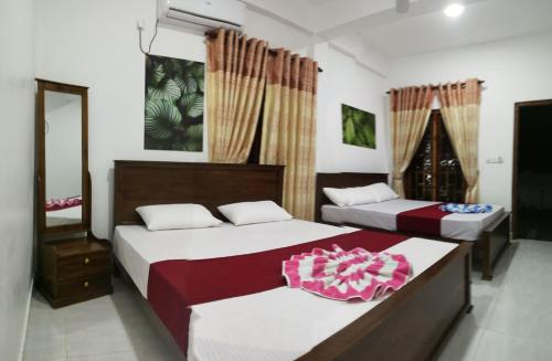 a bedroom with two beds and a mirror at Dive beach palace in Uppuveli