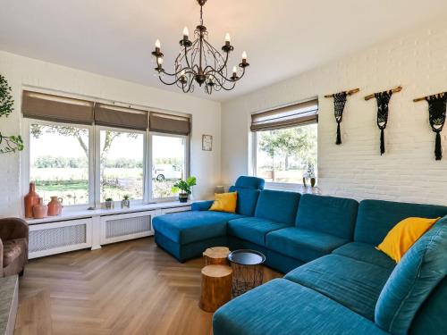 een woonkamer met een blauwe bank en een kroonluchter bij Relaxing Holiday Home in Hellendoorn with Garden in Hellendoorn