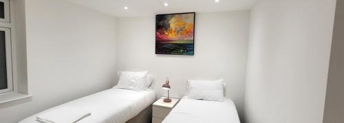 2 letti in una camera con pareti bianche di Garland Stylish Apartment 1 in Greater London a Londra