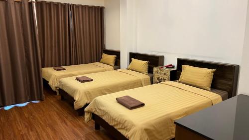 巴吞他尼Hotel IYA的配有棕色窗帘的酒店客房内的两张床