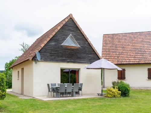 een huis met een tafel en stoelen en een paraplu bij Holiday home at Lacapelle Marival in Lacapelle-Marival