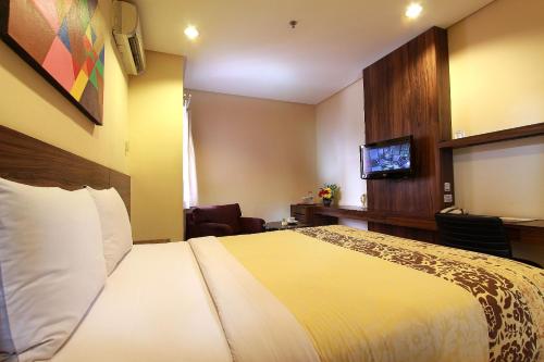 a hotel room with a bed and a flat screen tv at Prasada Mansion Sudirman in Jakarta