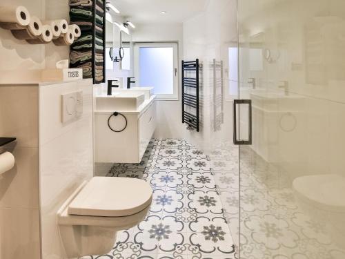 a white bathroom with a toilet and a sink at Holiday home by the Wadden Sea in Paesens