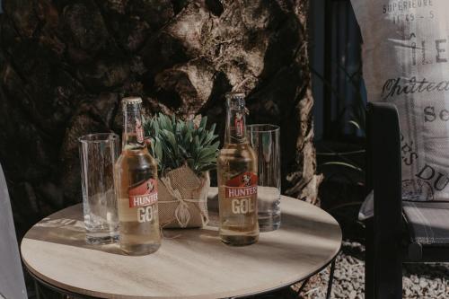 three bottles of beer on a table with glasses at Villa Rose Guesthouse & Venue in Bloemfontein