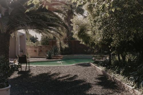 a swimming pool in a yard with palm trees at Villa Rose Guesthouse & Venue in Bloemfontein