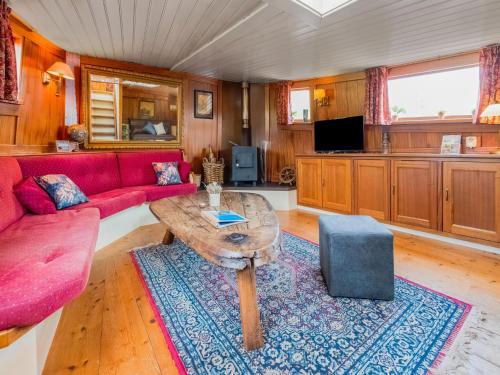 een woonkamer met een rode bank en een tafel bij Luxury boat in Kerkdriel in Kerkdriel