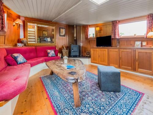 a living room with a red couch and a table at Luxury boat in Kerkdriel in Kerkdriel