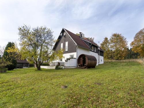 a black and white house with a barrel in a yard at Country cottage with Sauna and bubble bath in Kraslice