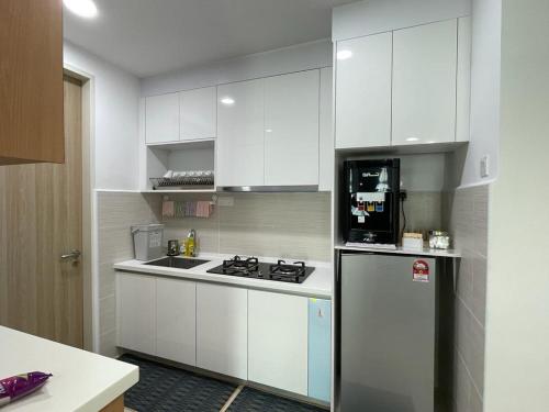 Una cocina con gabinetes blancos y un refrigerador. en Legasi Kampung Baru apartment by rumahrehat, en Kuala Lumpur