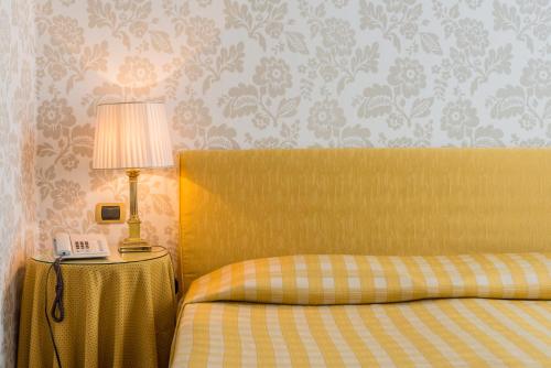 a bedroom with a bed and a lamp on a table at Albergo Alla Posta in Trieste