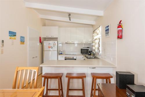 a kitchen with a counter and some wooden stools at Batehaven Beach House in Batehaven