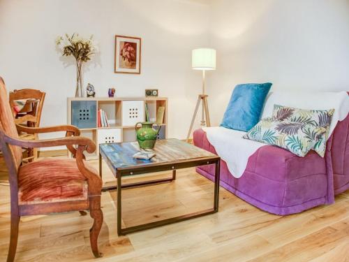 ein Wohnzimmer mit einem lila Sofa und einem Tisch in der Unterkunft Holiday home in Houtteville with garden in Picauville