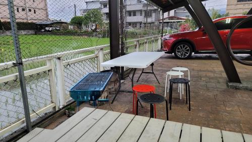une table et des tabourets sur un balcon avec une voiture dans l'établissement ChaoPingJia Homestay, à Luodong