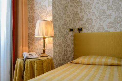 ein Schlafzimmer mit einem Bett mit einer Lampe und einem Telefon in der Unterkunft Albergo Alla Posta in Triest