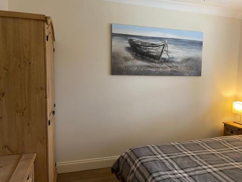 a bedroom with a painting of a boat on the wall at Waterfront House In The Heart Of St Neots in Saint Neots