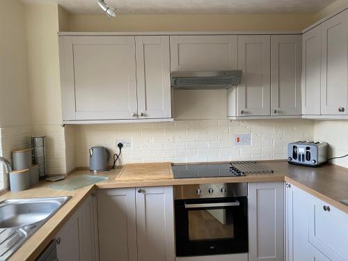 a kitchen with white cabinets and a stove top oven at Waterfront House In The Heart Of St Neots in Saint Neots