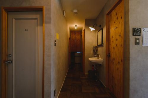 a hallway with a bathroom with a sink and a door at guesthouse SHIBAFU in Kamakura