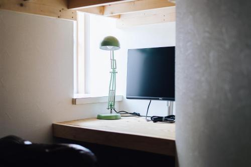 a room with a desk with a television and a lamp at guesthouse SHIBAFU in Kamakura