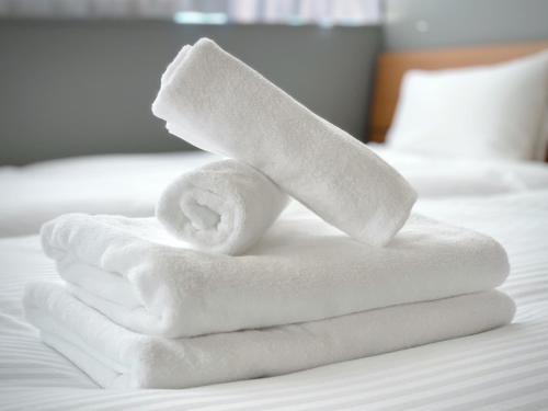 a pile of towels sitting on top of a bed at PRISM INN OGU in Tokyo