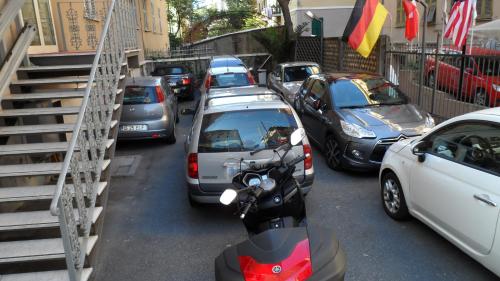 a row of parked cars and a scooter on a street at Hotel Boccascena in Genova
