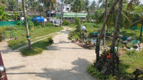 a dirt road with palm trees in a yard at Royal Beach Abode in Cochin